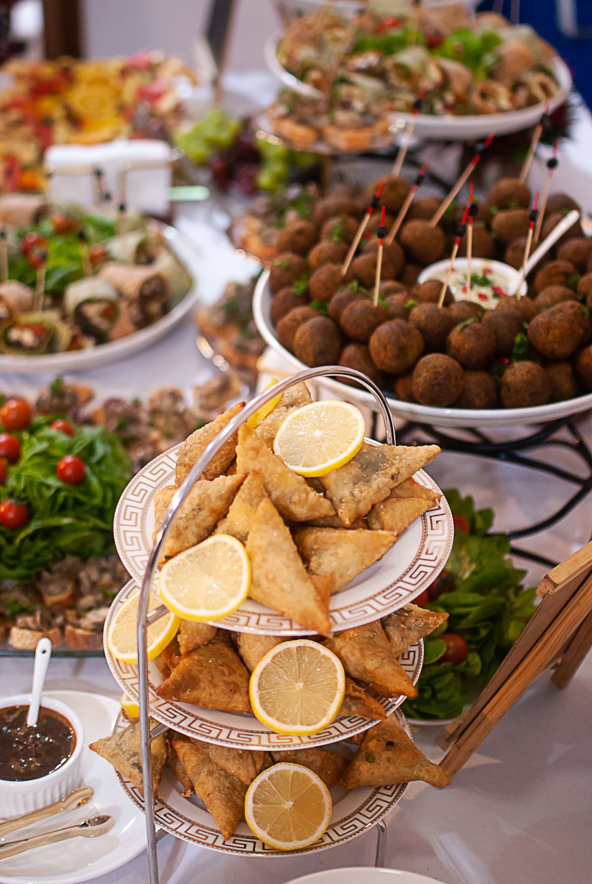 Bandejas de buffet com salgados, samosas e almôndegas decoradas com rodelas de limão