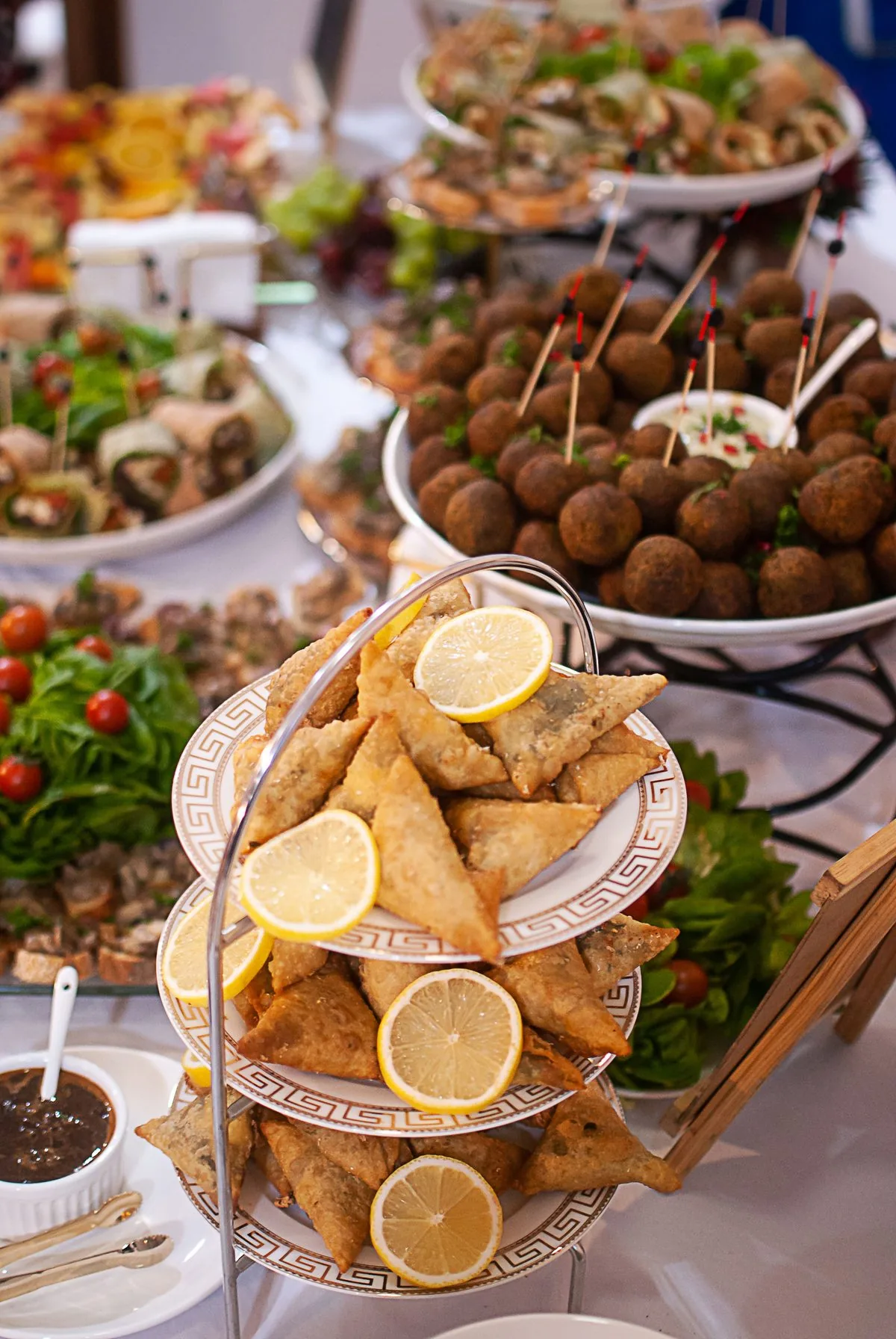 Bandejas de buffet com salgados, samosas e almôndegas decoradas com rodelas de limão
