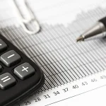 Calculadora e caneta sobre uma planilha financeira impressa