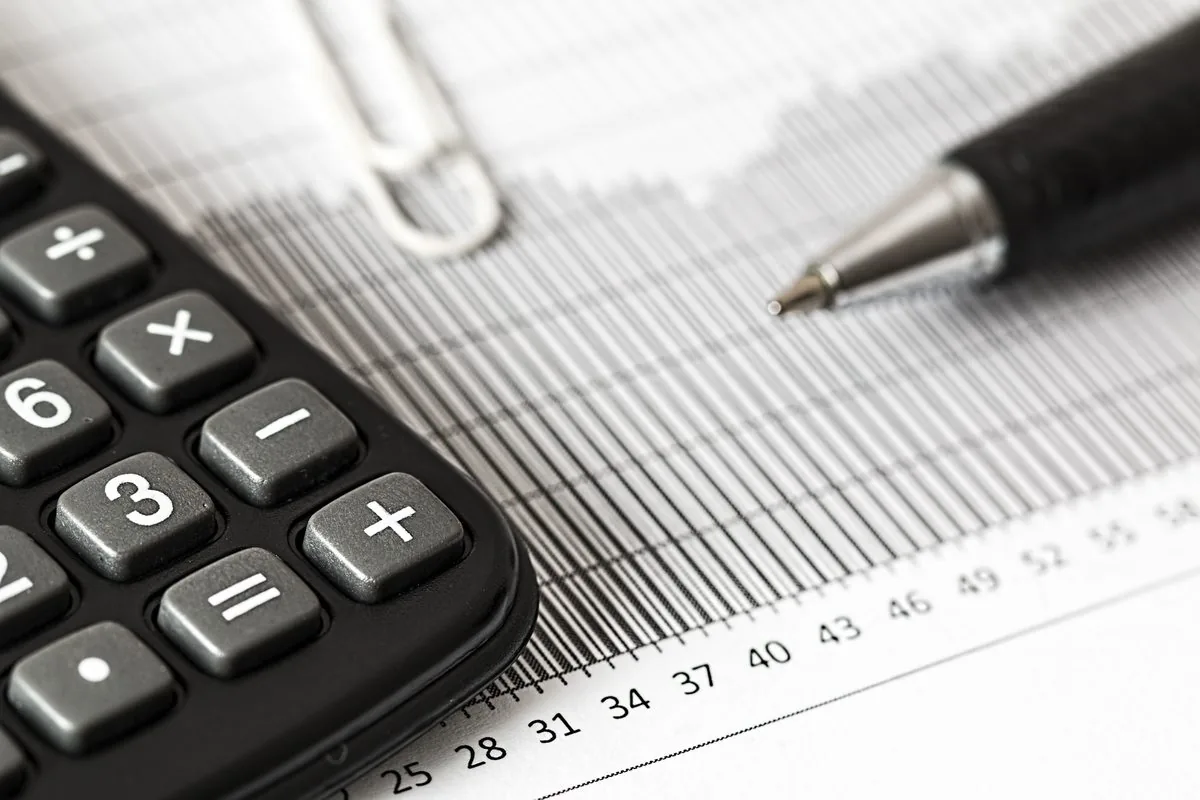 Calculadora e caneta sobre uma planilha financeira impressa