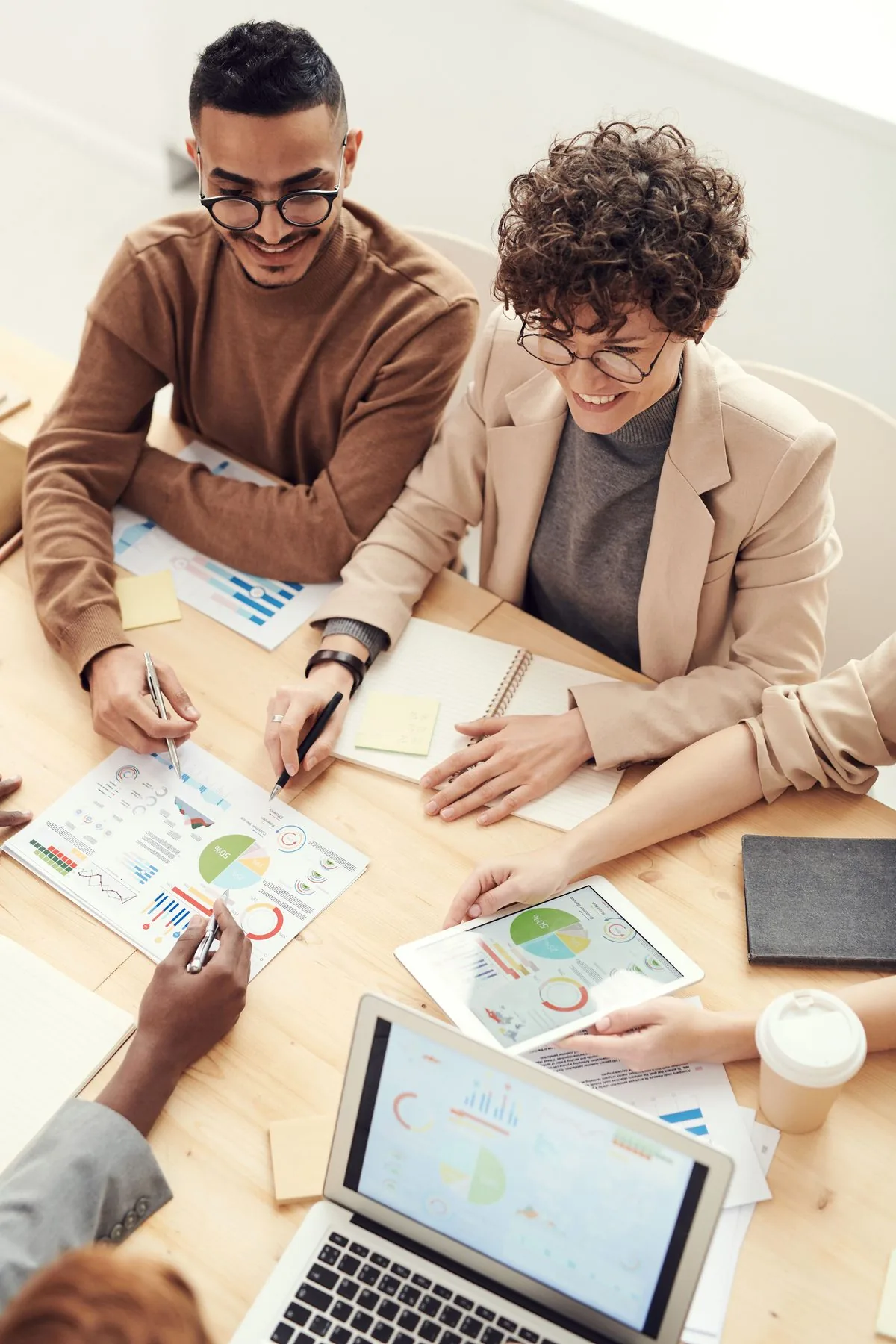 Equipe analisando gráficos e relatórios de negócio reunida em volta de uma mesa