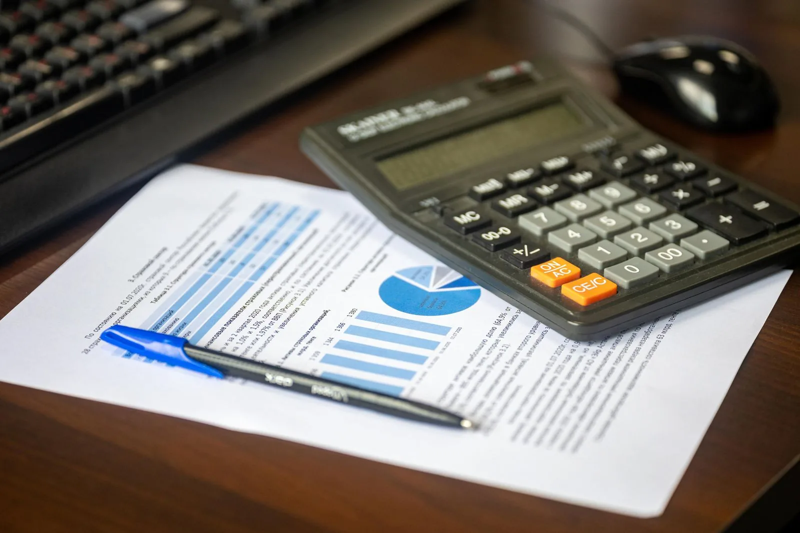 Calculadora e relatório financeiro sobre a mesa, representando a previsão de custo e lucro de um evento
