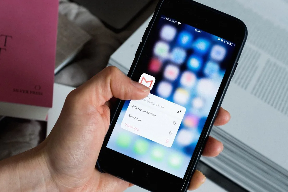 Mão segurando smartphone com ícone de e-mail em destaque na tela