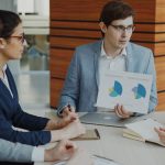 Equipe em reunião analisando dados antes de decidir, representando escolha estratégica de sistema de gestão