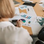 Profissionais analisando gráficos e planilhas financeiras com calculadora sobre a mesa