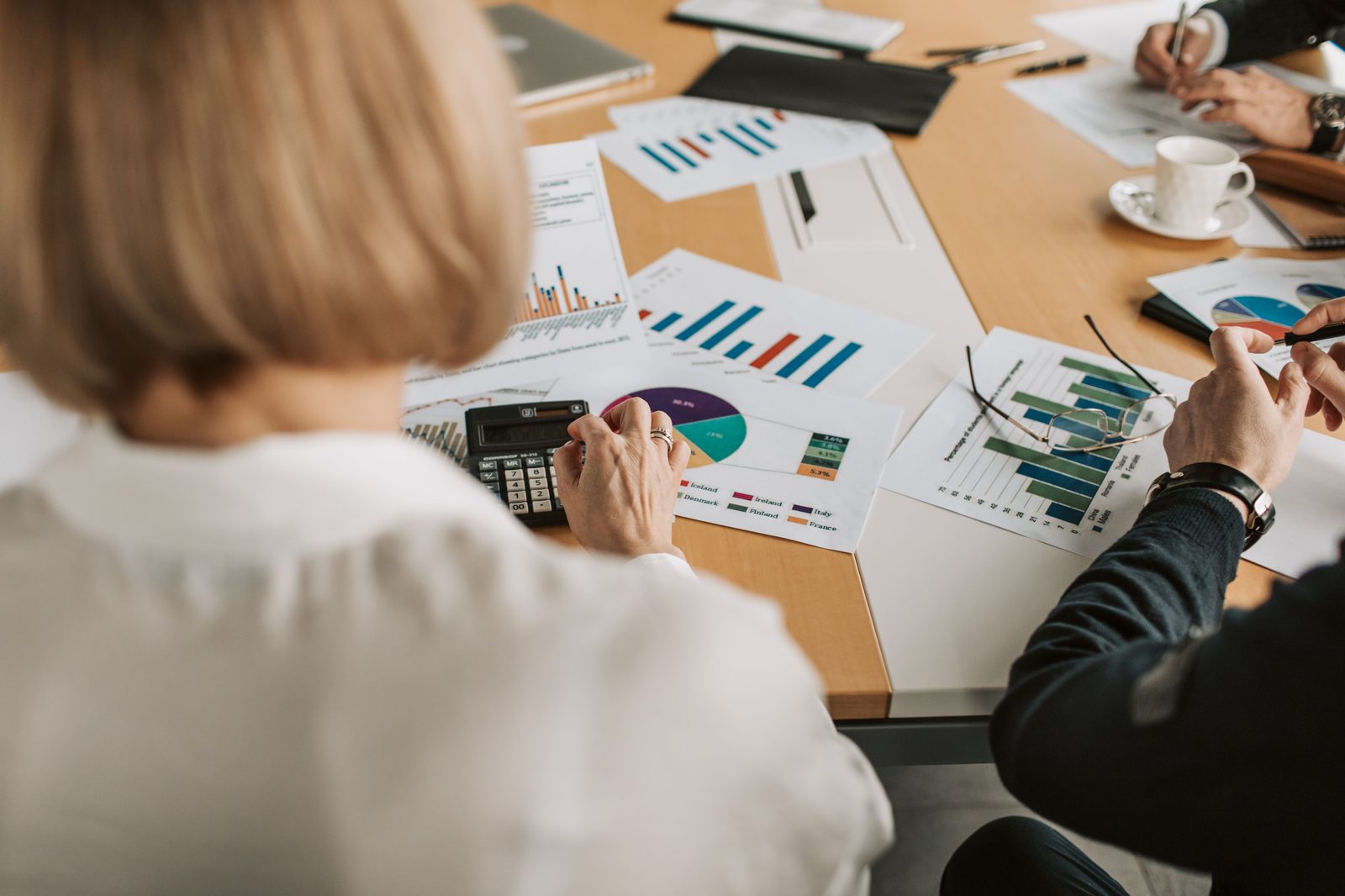 Profissionais analisando gráficos e planilhas financeiras com calculadora sobre a mesa