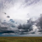 Nuvens escuras de tempestade sobre um campo aberto, representando o clima instável da primavera