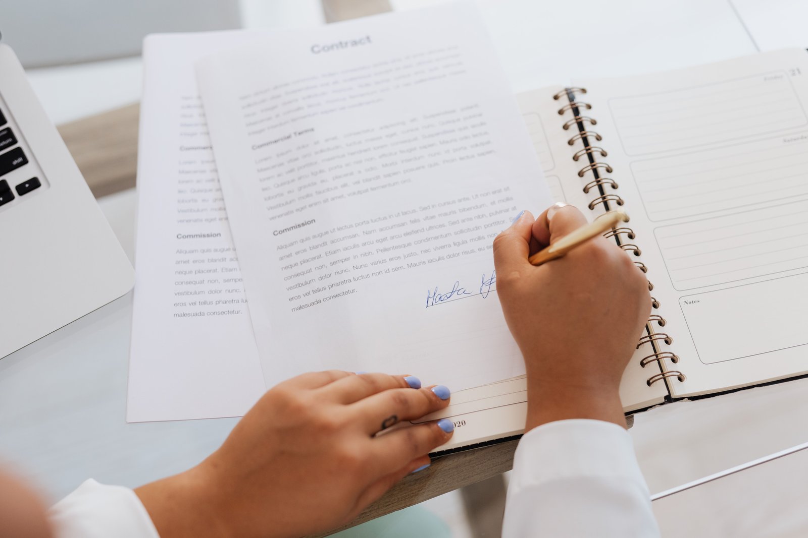 Pessoa assinando um contrato de prestação de serviço sobre uma mesa