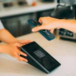Cliente pagando com o celular por QR Code em um terminal de pagamento no balcão