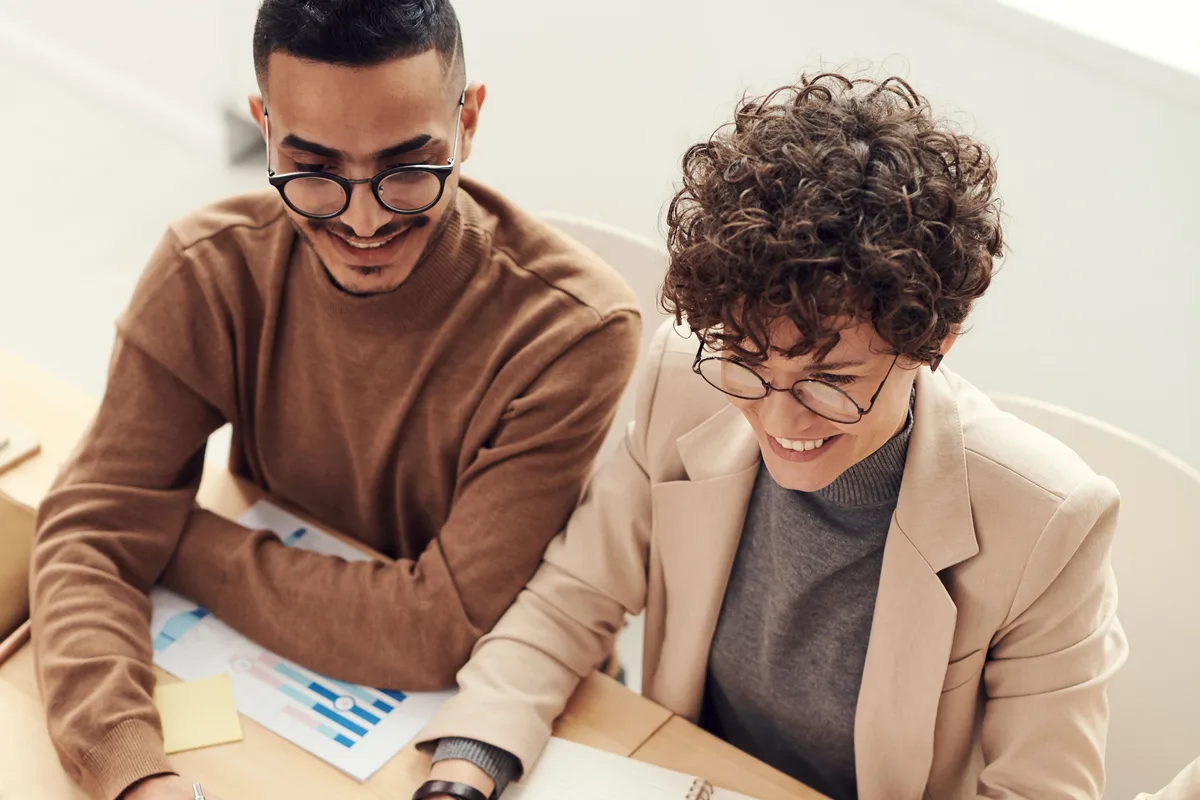 Equipe analisando gráficos e relatórios de negócio reunida em volta de uma mesa